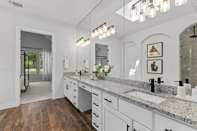 a spacious en suite bathroom with a granite countertop double vanity sink mirror and