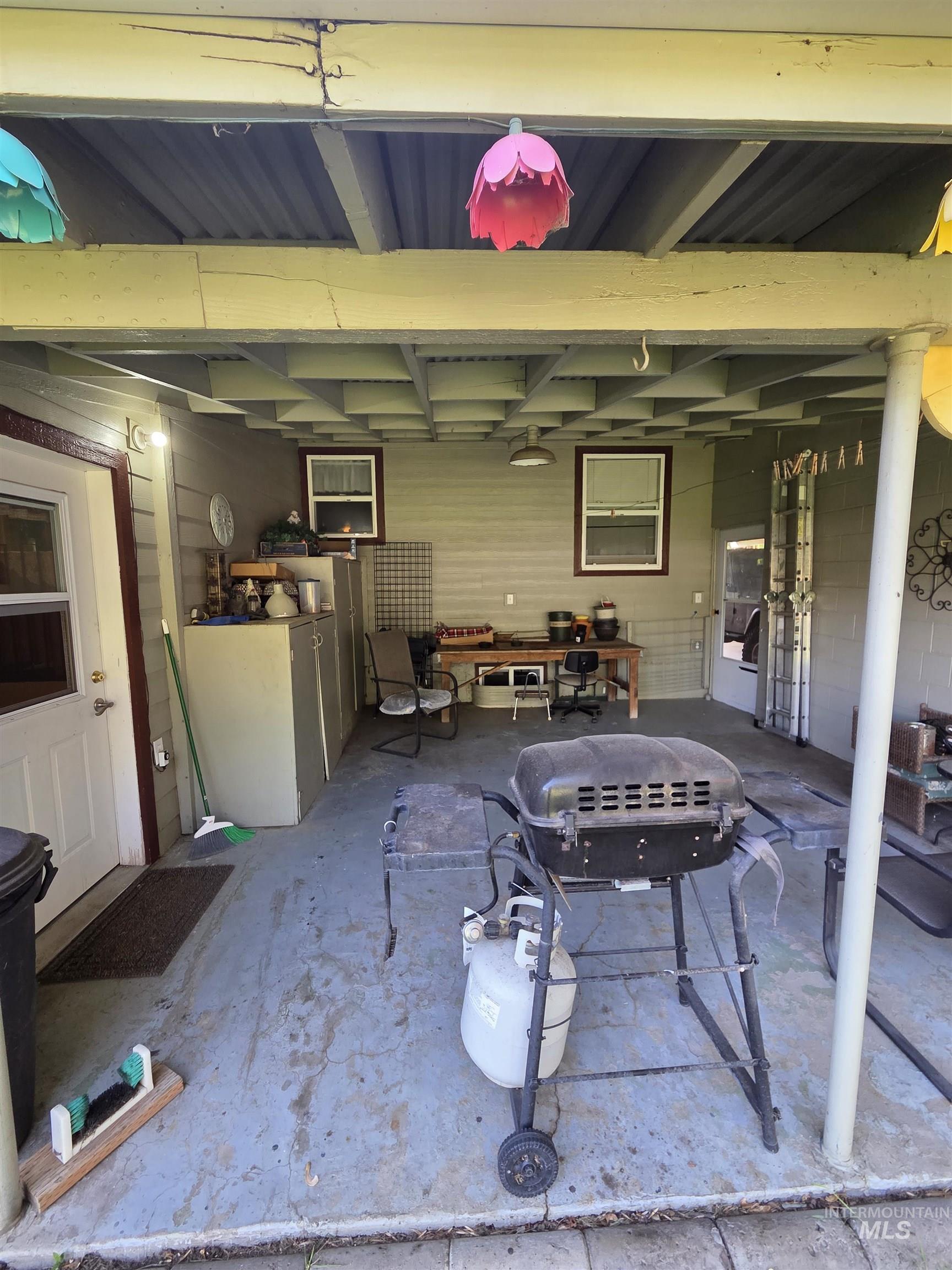 109 South 3rd Street Pomeroy, WA 99347 - Photo 31 of 36 Covered patio area with a concrete floor, featuring a white door with an integrated window, horizontal siding, and multiple windows with white blinds