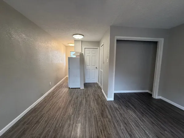 a view of an empty room with wooden floor and a bathroom