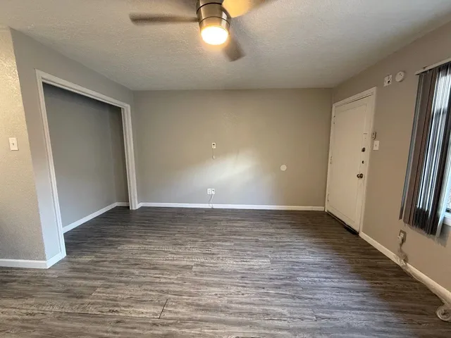 a view of an empty room with window and wooden floor