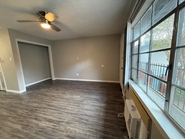 a view of an empty room with window and wooden floor