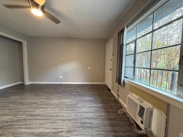 a view of an empty room with wooden floor and windows