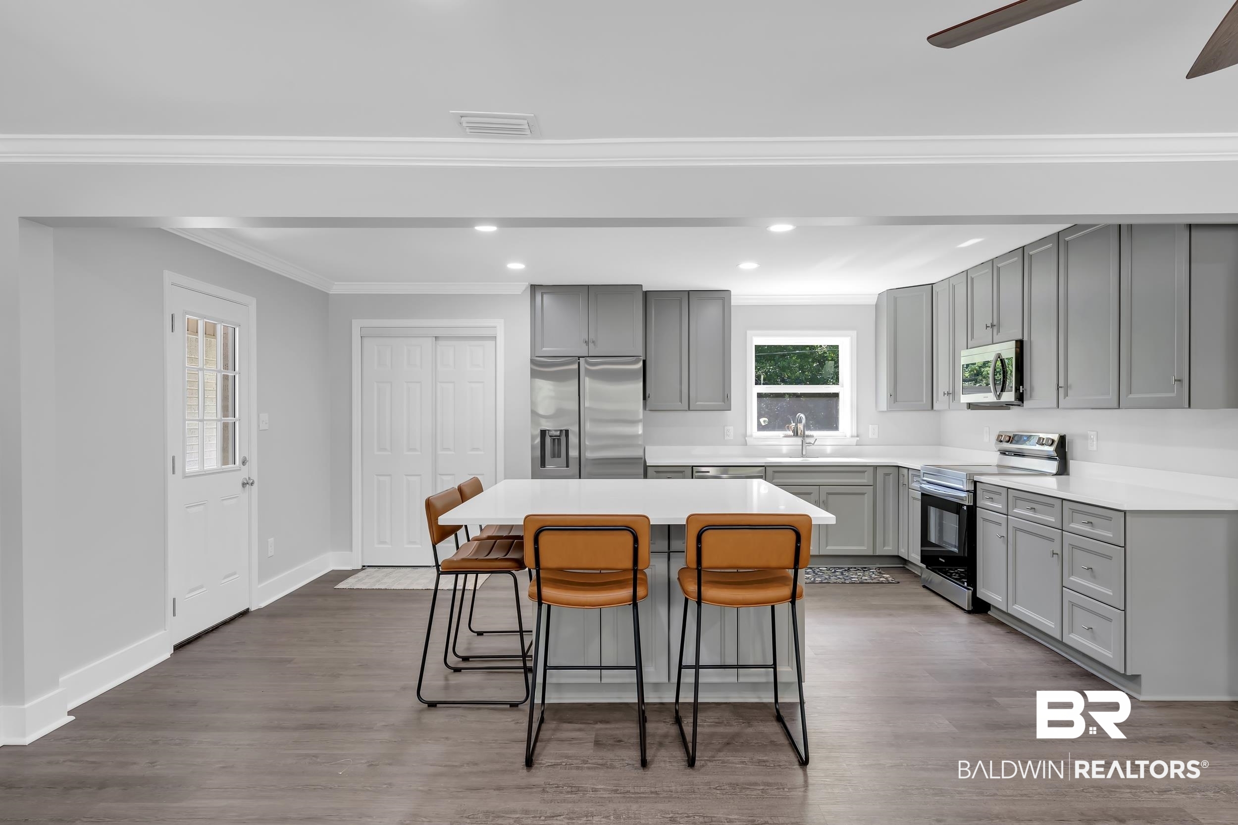 2712 Shelton Beach Rd Extension Mobile, AL 36613 - Photo 9 of 24 Spacious open-concept kitchen featuring a large central island, gray shaker cabinetry, stainless steel appliances, white countertops, and wood-finish flooring