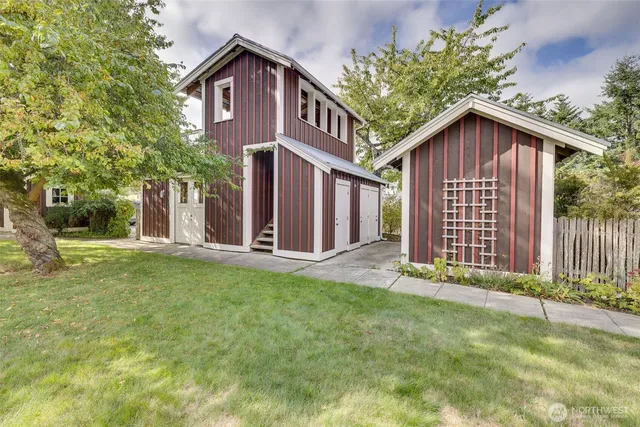 a view of a house with wooden fence and large trees