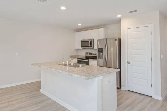 a kitchen with kitchen island a sink appliances and cabinets