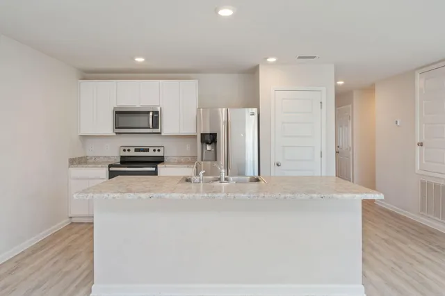 a kitchen with stainless steel appliances granite countertop a refrigerator a stove and a sink