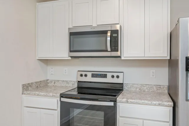 a kitchen with granite countertop white cabinets and stainless steel appliances