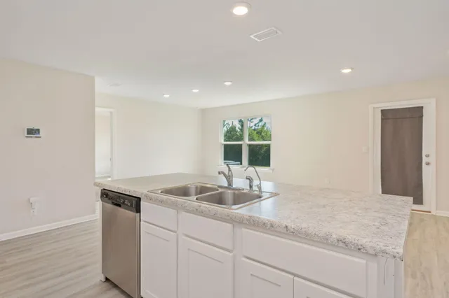 a kitchen with granite countertop white cabinets and a sink