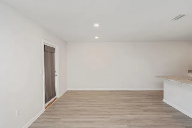 a view of an empty room with wooden floor and closet