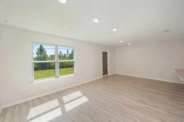 a view of an empty room with a window and wooden floor