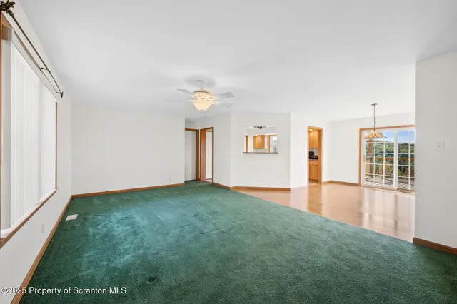 a view of an empty room with window and wooden floor