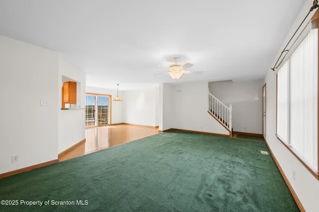an empty room with a chandelier fan and windows