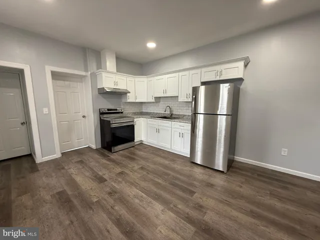 a kitchen with a refrigerator a stove top oven and white cabinets