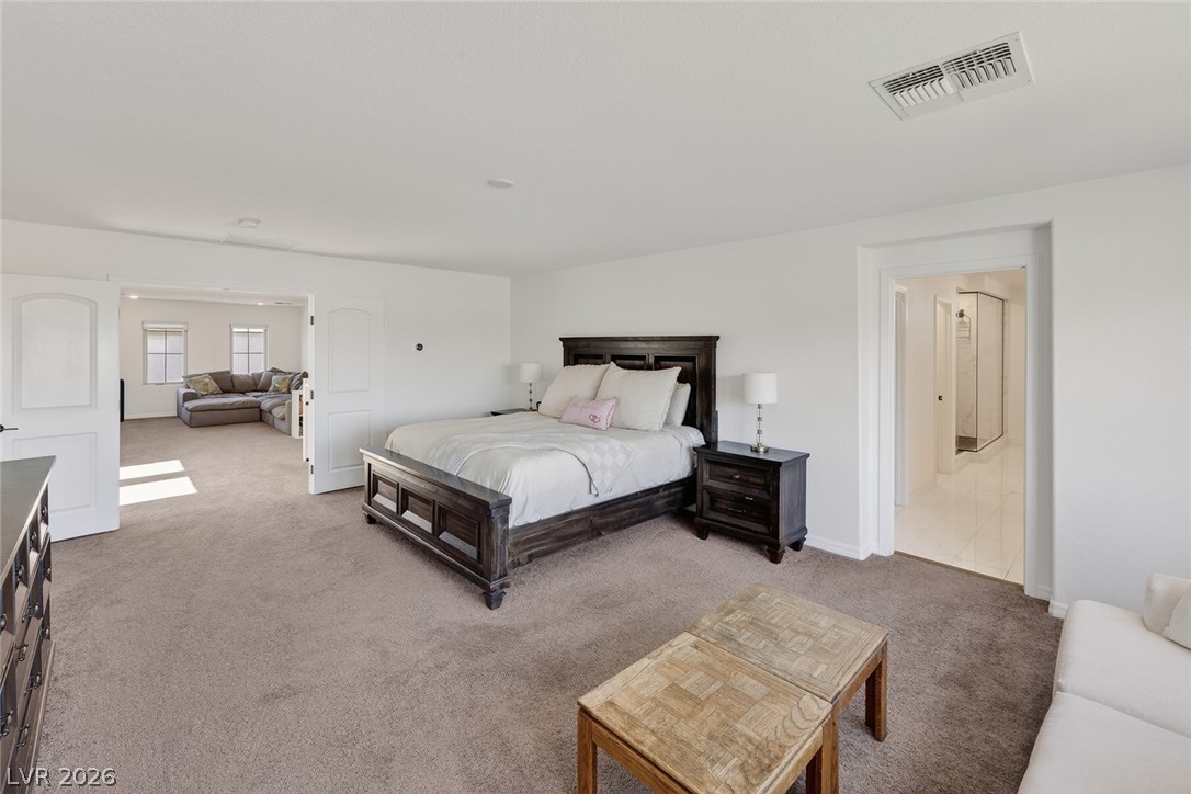 10446 Emerald Rye Street Las Vegas, NV 89183 - Photo 23 of 37 A spacious primary suite features soft carpeting, high ceilings, and a private attached living area.