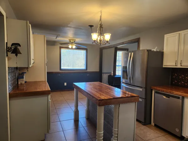 a kitchen with stainless steel appliances granite countertop a refrigerator a sink dishwasher a stove and a dining table with wooden floor