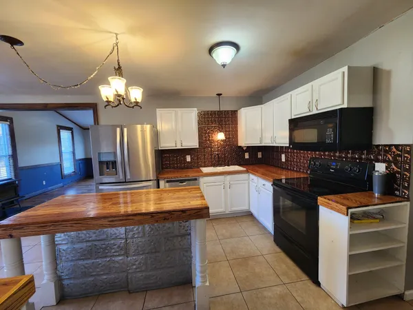 a large kitchen with stainless steel appliances wooden cabinets a stove and a sink