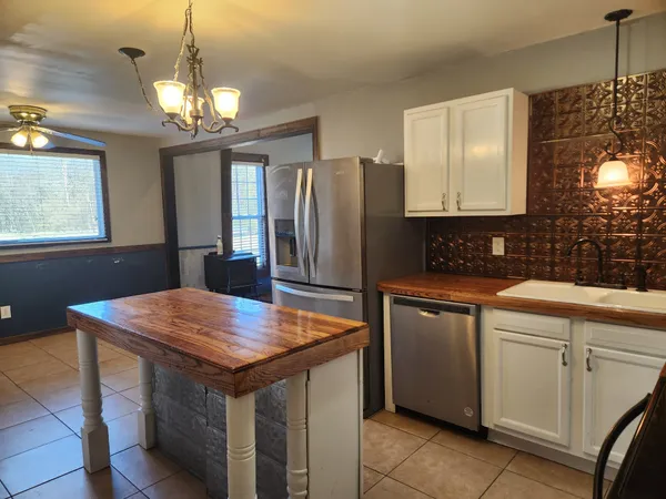 a kitchen with stainless steel appliances granite countertop wooden cabinets a refrigerator a sink a stove and island