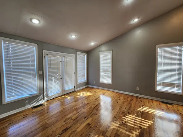 a view of an empty room with wooden floor and a window