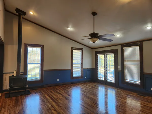 an empty room with wooden floor and windows