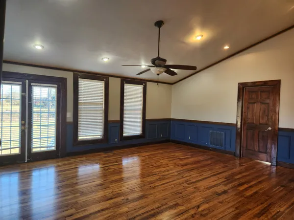 a view of an empty room with a window and wooden floor