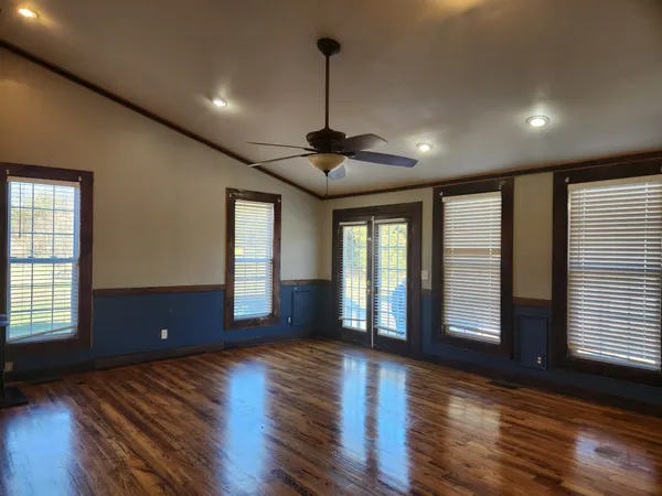 a view of an empty room with wooden floor and a window