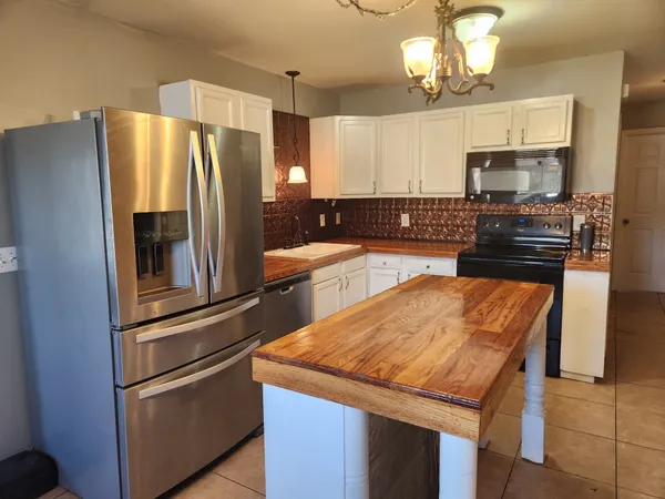 a kitchen with stainless steel appliances granite countertop a refrigerator a stove and a sink