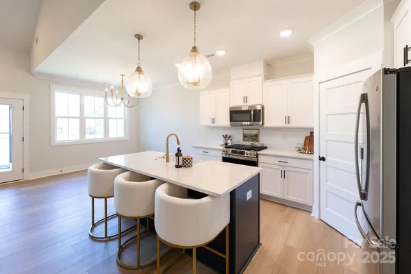 a kitchen with stainless steel appliances granite countertop a kitchen island a stove a table and chairs