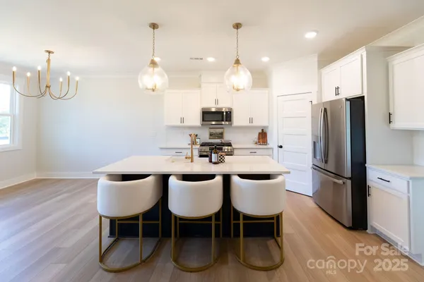 a kitchen with stainless steel appliances granite countertop a dining table chairs refrigerator and sink