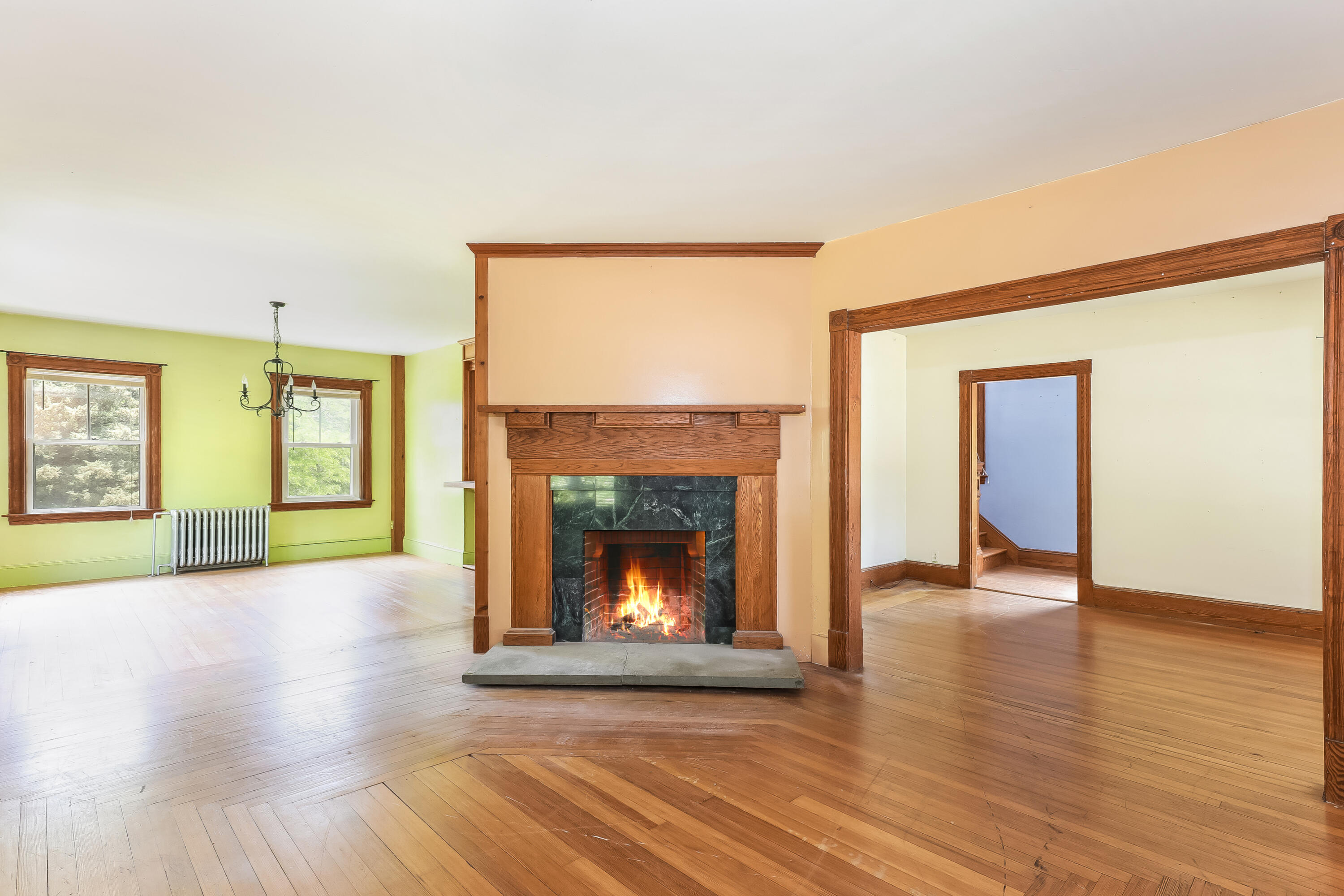 a view of an empty room with wooden floor fireplace and a window
