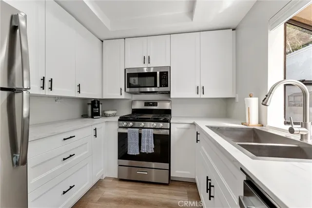 a kitchen with granite countertop white cabinets and stainless steel appliances