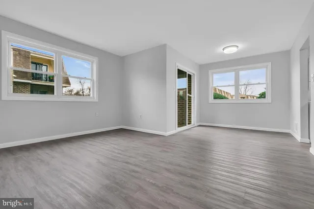 an empty room with wooden floor and windows
