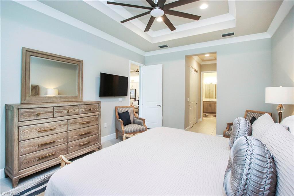11857 Hydrangea Place Naples, FL 34120 - Photo 17 of 50 a bedroom with a bed and a flat tv screen on dresser