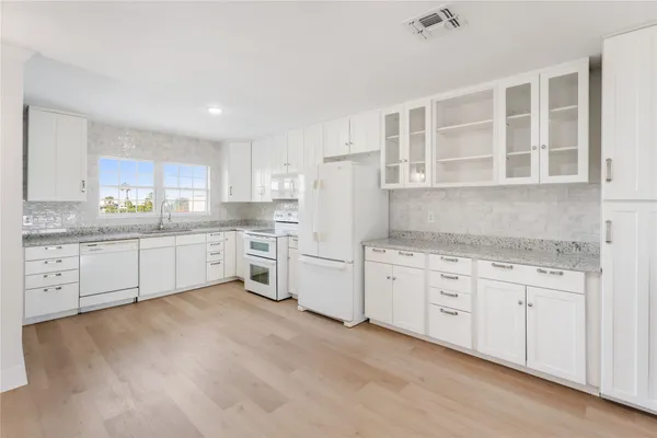 a kitchen with granite countertop cabinets sink and white appliances