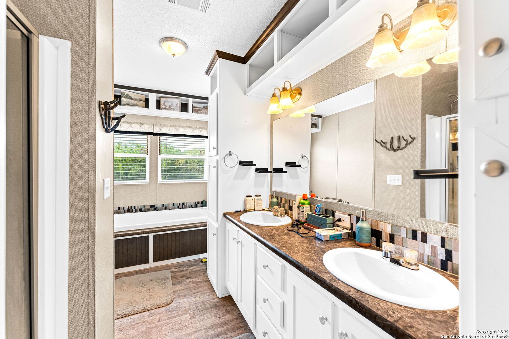 1979 County Road 651 Devine, TX 78016 - Photo 24 of 52 a large bathroom with a granite countertop double vanity sink a mirror and a bathtub