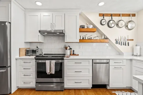 a kitchen with stainless steel appliances granite countertop a stove and a white cabinets