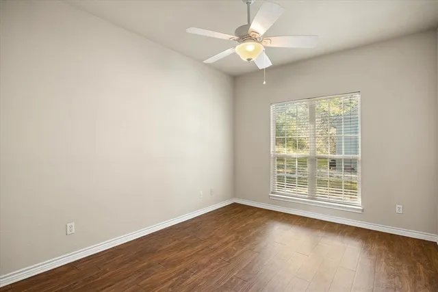 an empty room with wooden floor and window