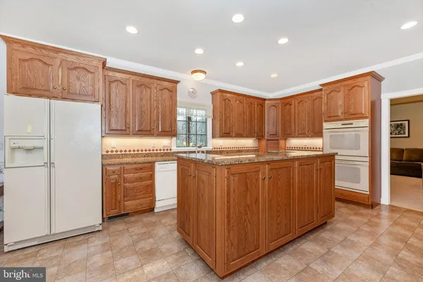 a kitchen with kitchen island granite countertop wooden cabinets and white appliances