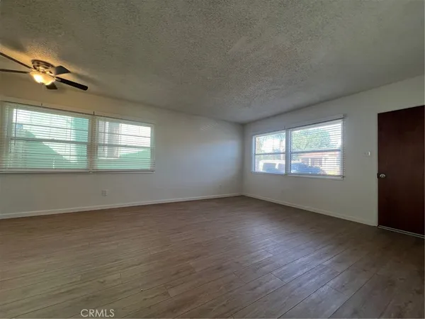 an empty room with wooden floor fan and windows