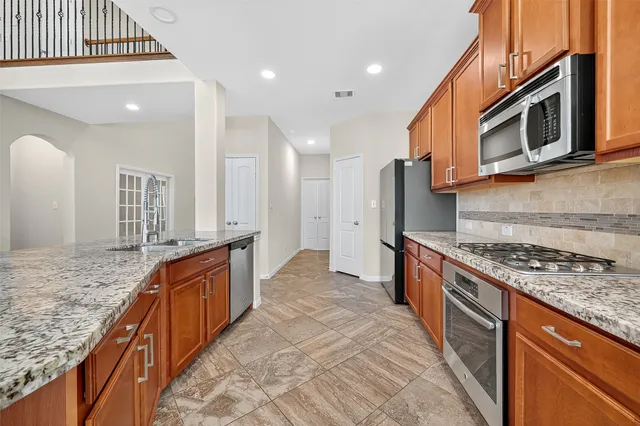 a large kitchen with stainless steel appliances granite countertop a stove and a sink