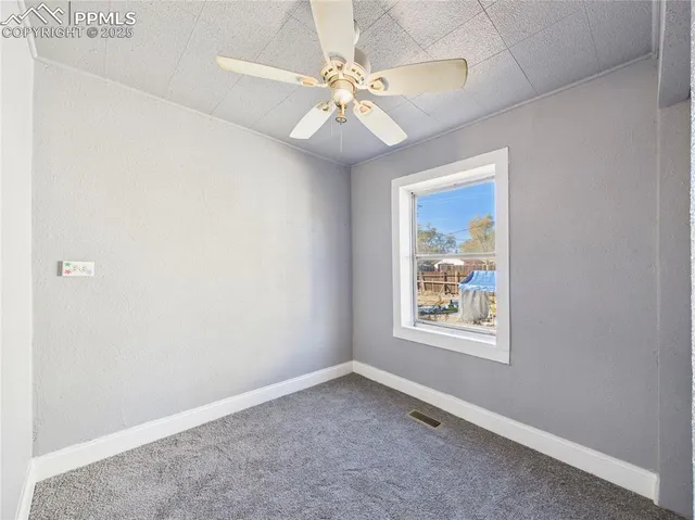 an empty room with a window and a fan