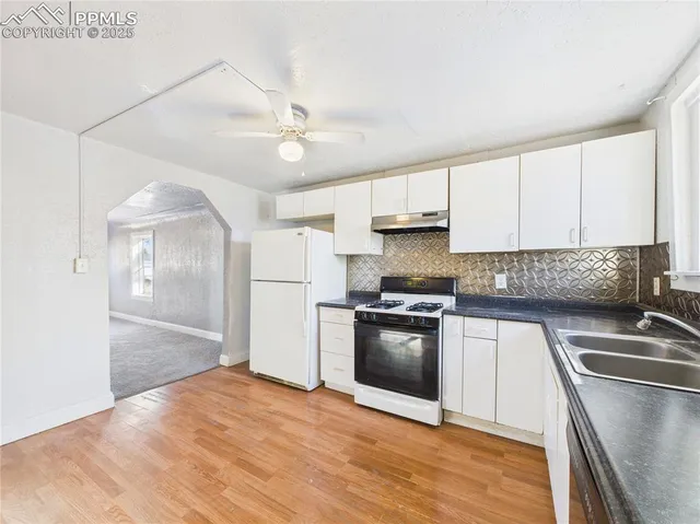 a kitchen with stainless steel appliances granite countertop a sink a stove a refrigerator with grey cabinets