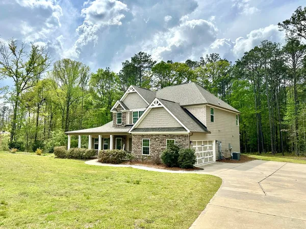 a front view of a house with a garden and trees
