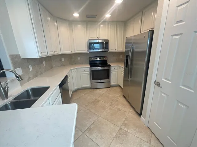 a kitchen with stainless steel appliances granite countertop a refrigerator and a sink