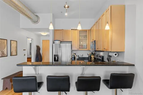 a kitchen with granite countertop a refrigerator a stove a sink a counter space and cabinets