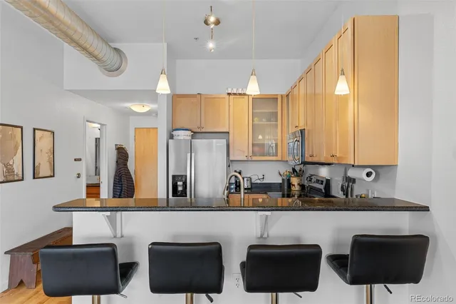 a kitchen with granite countertop a refrigerator a stove a sink a counter space and cabinets