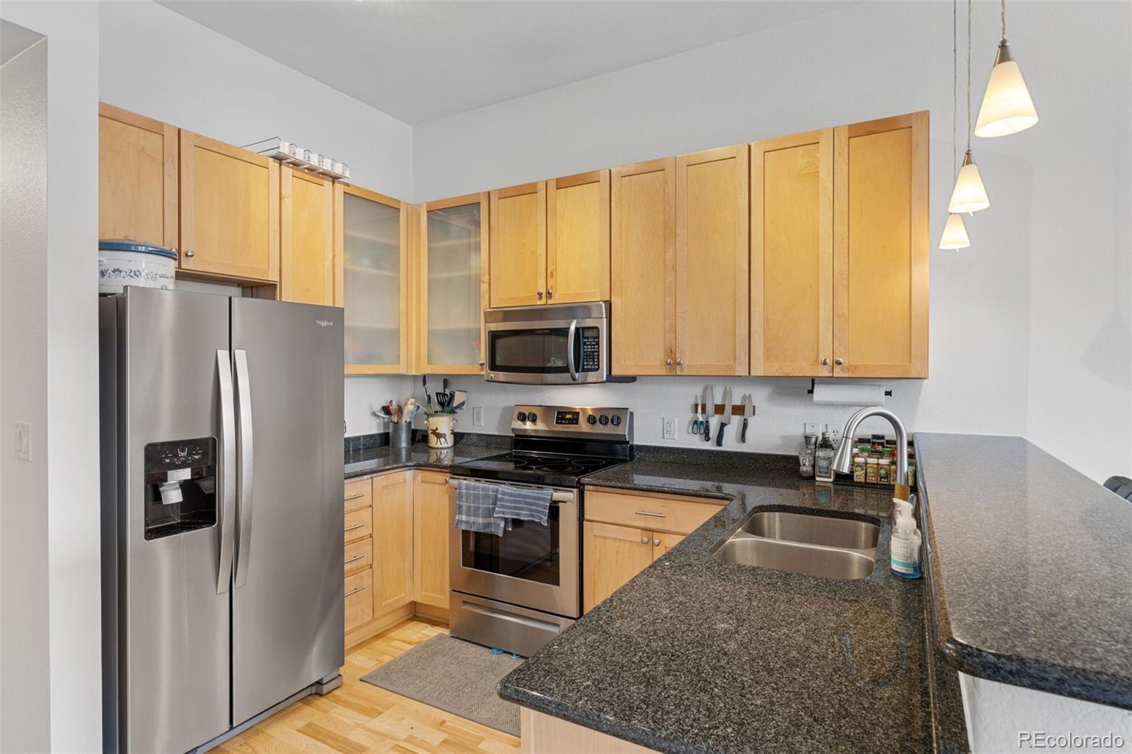 1555 Central Street, Unit 306 Denver, CO 80211 - Photo 19 of 36 a kitchen with granite countertop a refrigerator a stove a sink a counter space and cabinets
