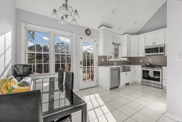 a kitchen with stainless steel appliances granite countertop a stove top oven a sink dishwasher a dining table and chairs with wooden floor