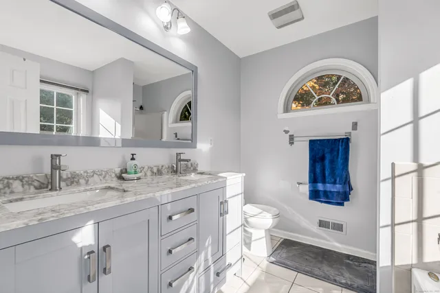 a bathroom with a granite countertop toilet sink and mirror
