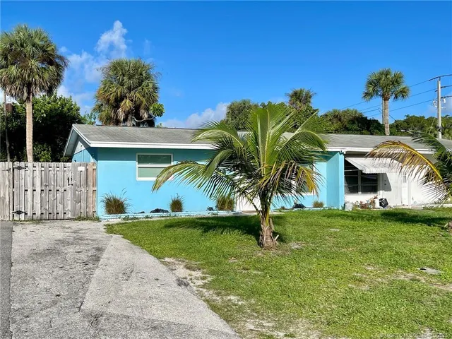 a palm tree sitting in front of a house with a big yard