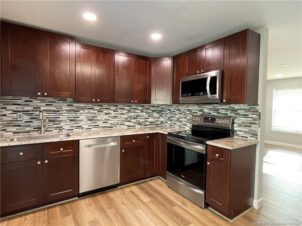 406 Robalo Court Stuart, FL 34996 - Photo 7 of 22 a kitchen with stainless steel appliances granite countertop wooden cabinets a stove top oven a sink and dishwasher